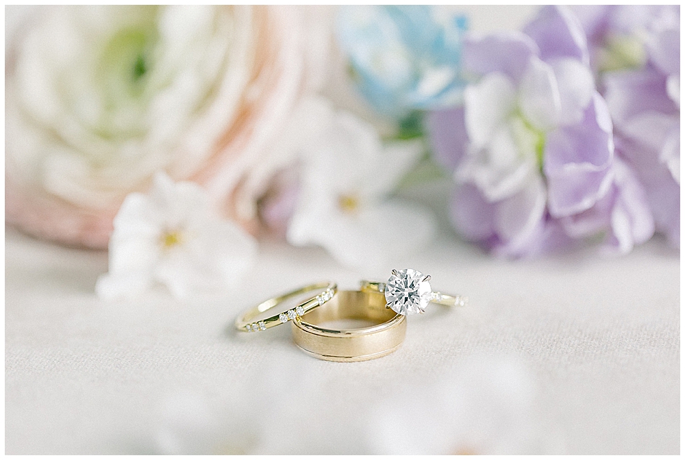 Pastel florals surrounding a traditional, classic wedding band set with solitaire diamond engagement ring and gold band | Georgia wedding photographer