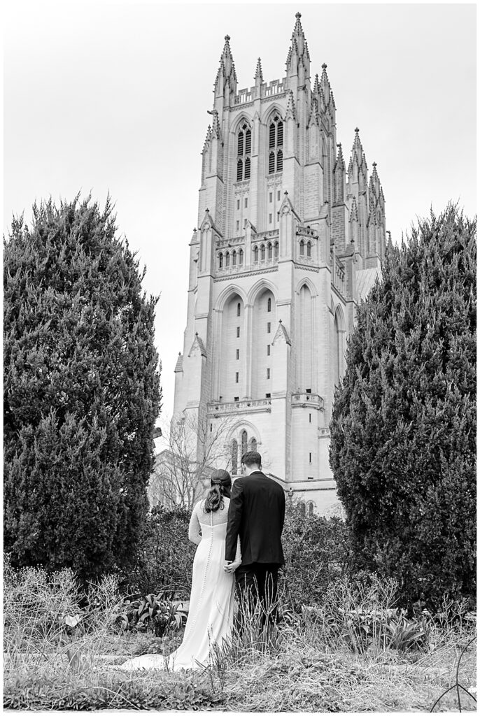 Black and white photo of a bride and groom praying in front of the National Cathedral in Washington DC